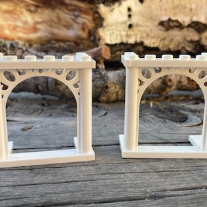 May include: Two white plastic archways with decorative details. The archways are made of Lego bricks and are designed to be used as building blocks.