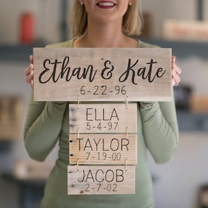 A cute mom holding a family list sign with the names and dates of birth of her children and her and her husband's wedding date.