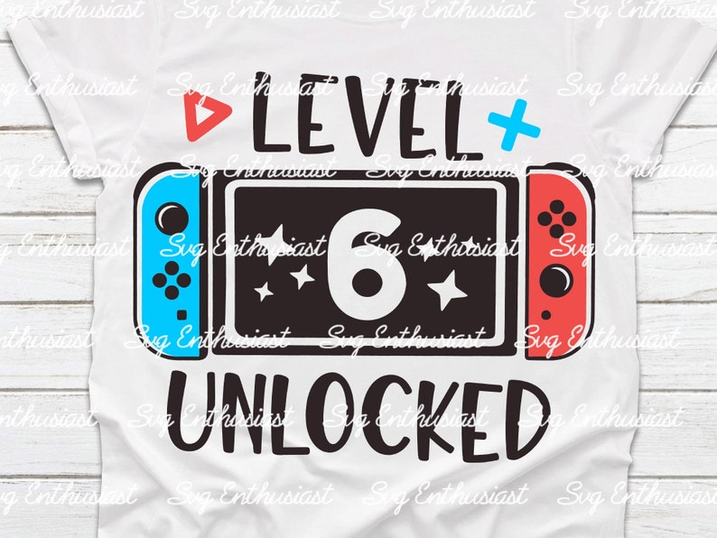 May include: A white t-shirt featuring a blue and red Nintendo Switch controller graphic. The text "Level 6 Unlocked" is printed in black on the shirt.