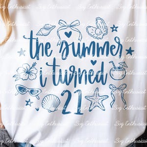 Può includere: Una t-shirt bianca con un design grafico blu scuro con il testo 'the summer i turned 21'. Il design include illustrazioni di una conchiglia, un fiocco, un'ostrica con una perla, un fiore di ibisco, una bevanda tropicale, occhiali da sole e una stella marina.