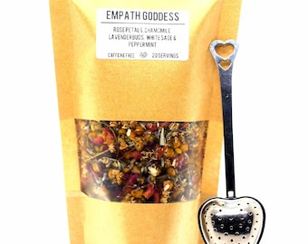 May include: A brown paper bag with a label that reads "Empath Goddess Rose Petals, Chamomile, Lavenderbuds, White Sage & Peppermint Caffeine Free 20 Servings". The bag contains a blend of dried herbs and flowers. A silver heart-shaped tea infuser is included.