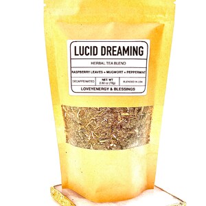 May include: A brown paper pouch with a label that reads "Lucid Dreaming Herbal Tea Blend" and lists the ingredients as "Raspberry Leaves + Mugwort + Peppermint". The label also states "Decaffeinated", "Net Wt. 2.80 oz (78g)", "Blended in USA", and "Loveyenergy & Blessings". The pouch is filled with dried herbs.