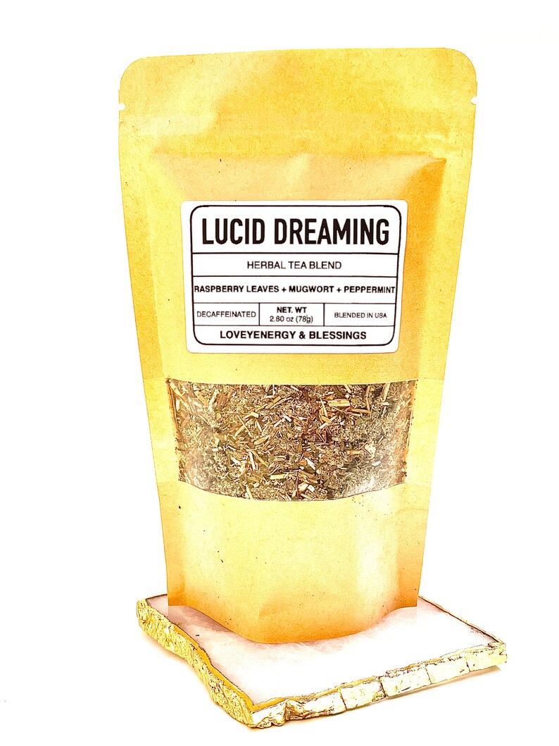 May include: A brown paper pouch with a label that reads "Lucid Dreaming Herbal Tea Blend" and lists the ingredients as "Raspberry Leaves + Mugwort + Peppermint". The label also states "Decaffeinated", "Net Wt. 2.80 oz (78g)", "Blended in USA", and "Loveyenergy & Blessings". The pouch is filled with dried herbs.