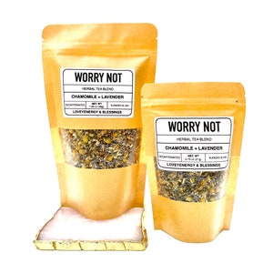 May include: Two brown paper bags with a white label that reads "WORRY NOT" and "HERBAL TEA BLEND" with the text "CHAMOMILE + LAVENDER" in black. The bags are filled with dried herbs and the smaller bag has a net weight of 0.75 oz (21g).