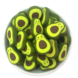 May include: A bowl filled with green and brown silicone avocado-shaped beads with happy faces.