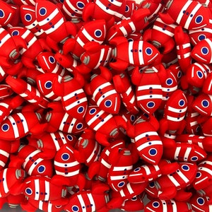 May include: A large group of red and white rocket-shaped silicone beads. The rockets have blue details and are arranged in a random pattern.