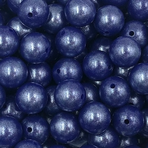 May include: A close-up of a group of large, round, blue silicone beads with a metallic sheen. The beads are arranged in a random pattern, creating a textured surface.