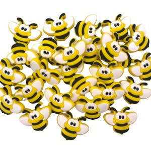 May include: A group of 25 yellow and black bee-shaped charms with white eyes and wings.