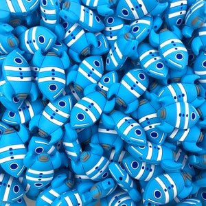 May include: A large group of blue and white rocket-shaped silicone beads. The beads have a white stripe and a blue circle on each side.
