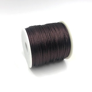 May include: A spool of dark brown waxed cord, perfect for jewelry making, macrame, or crafts.