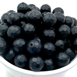 May include: A bowl filled with black silicone beads. The beads are faceted and have a matte finish.