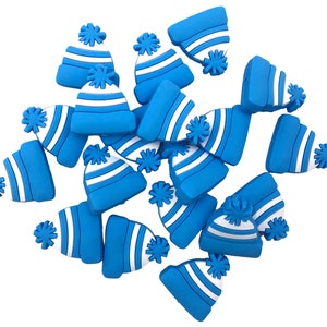 May include: A collection of blue and white miniature winter hats with pom-poms. The hats are a vibrant blue with white stripes and a white pom-pom on top. The hats are scattered against a white background.