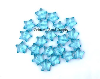 May include: A group of light blue star-shaped glass beads. The beads are translucent and have a slightly iridescent finish.  "Princess Bead Supply" is printed on the white background.