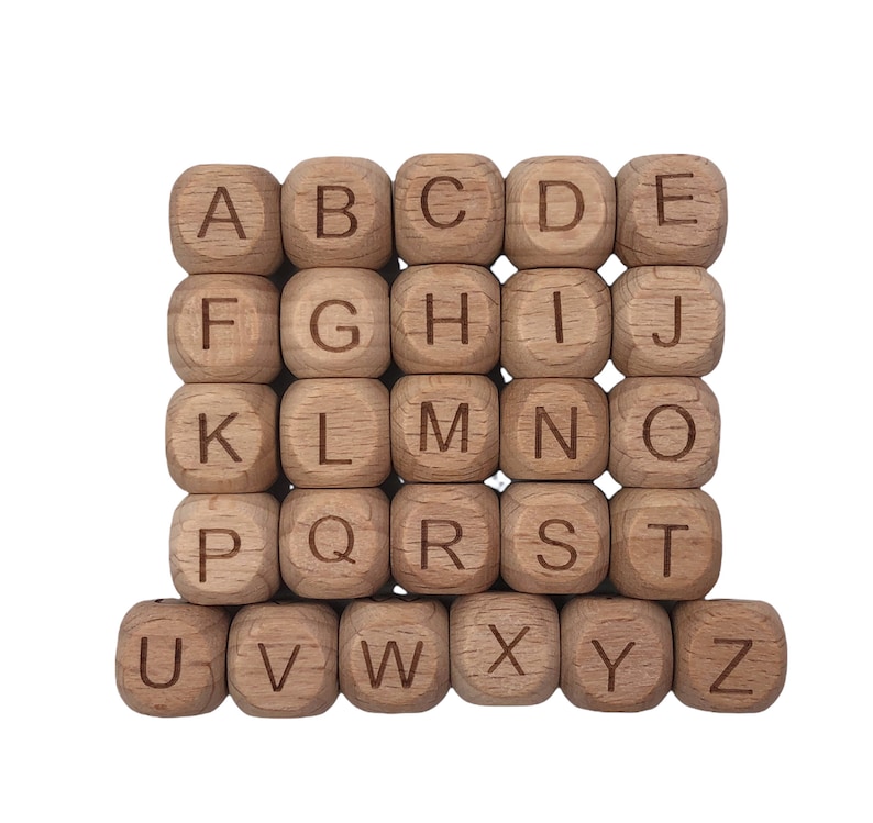 May include: A grid of 26 wooden alphabet blocks, each with a letter from A to Z engraved on one side. The blocks are light brown with visible wood grain, arranged in a neat, organized pattern against a white background.