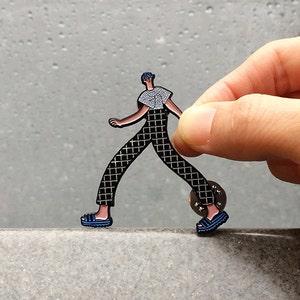 Walking boy wearing checker pants and t-shirt, adidas style slippers enamel pin.