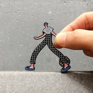 Walking boy wearing checker pants and t-shirt, adidas style slippers enamel pin.