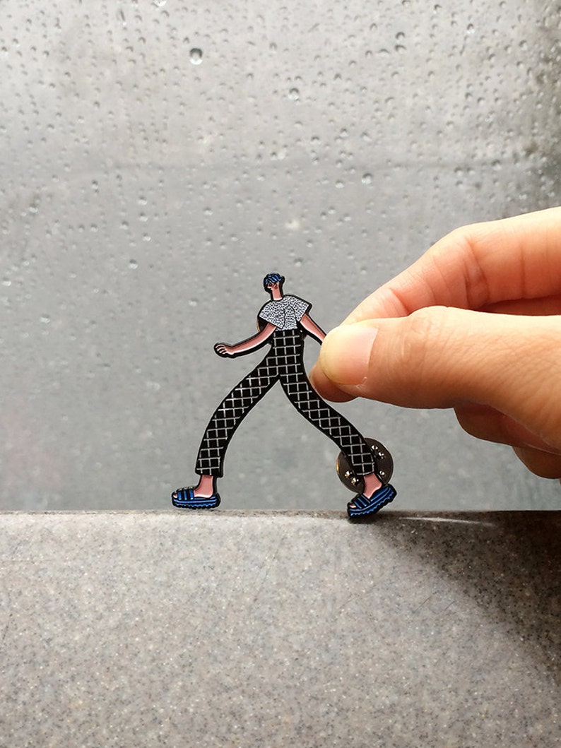 Walking boy wearing checker pants and t-shirt, adidas style slippers enamel pin.