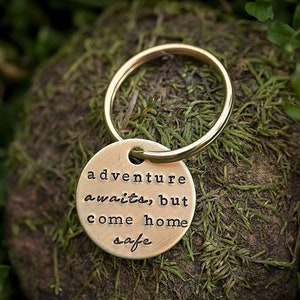 May include: A gold-colored keychain with a round tag that reads "adventure awaits, but come home safe".