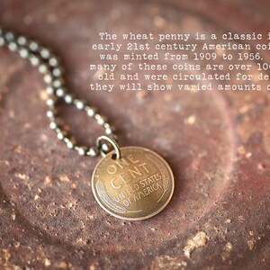 May include: A copper-colored pendant necklace featuring a vintage one-cent coin with the inscription "ONE CENT UNITED STATES OF AMERICA".