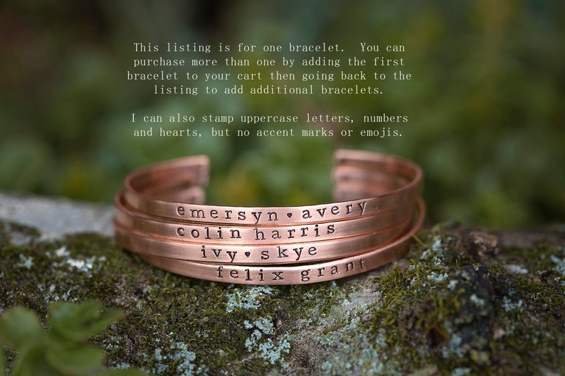 May include: Copper-colored bracelets with stamped names and a heart symbol. The bracelets are stacked on top of each other. The text on the bracelets includes names like "emersyn avery" and "colin harris".