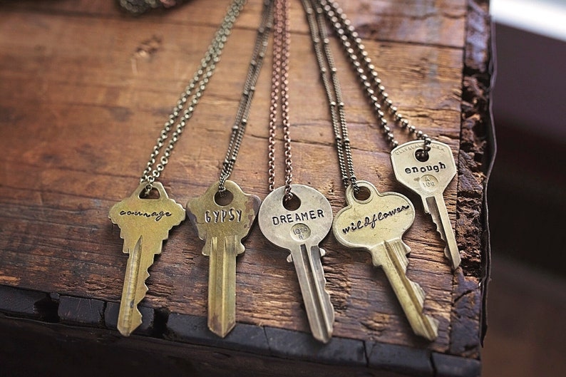 A vintage key hand-stamped with the word of your choice and attached to a brass, copper or silver chain.