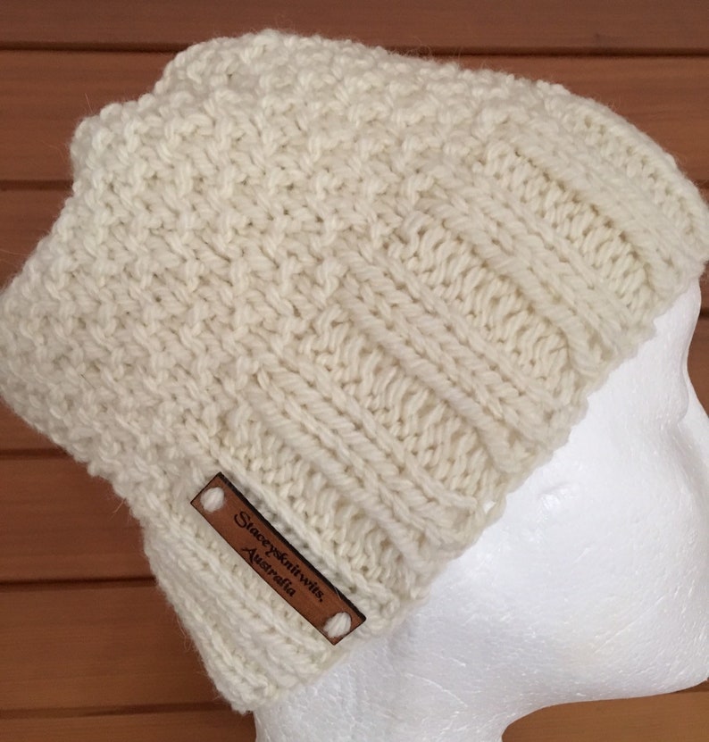 May include: A white knitted beanie with a brown leather label that reads "Stacey Knit Wits, Australia".