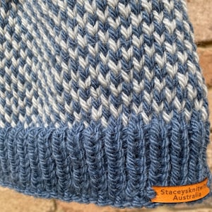 May include: A blue and white knitted hat with a chevron pattern. The hat has a brown leather label that says "Stacey's Knit with Australia".