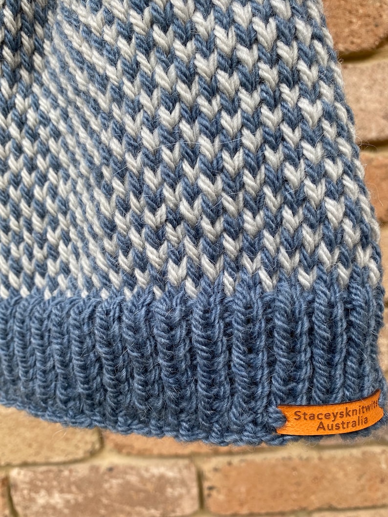 May include: A blue and white knitted hat with a chevron pattern. The hat has a brown leather label that says "Stacey's Knit with Australia".