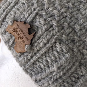 May include: Gray knitted beanie with a wooden tag that says "Handmade with love by Cozy Knit Co."