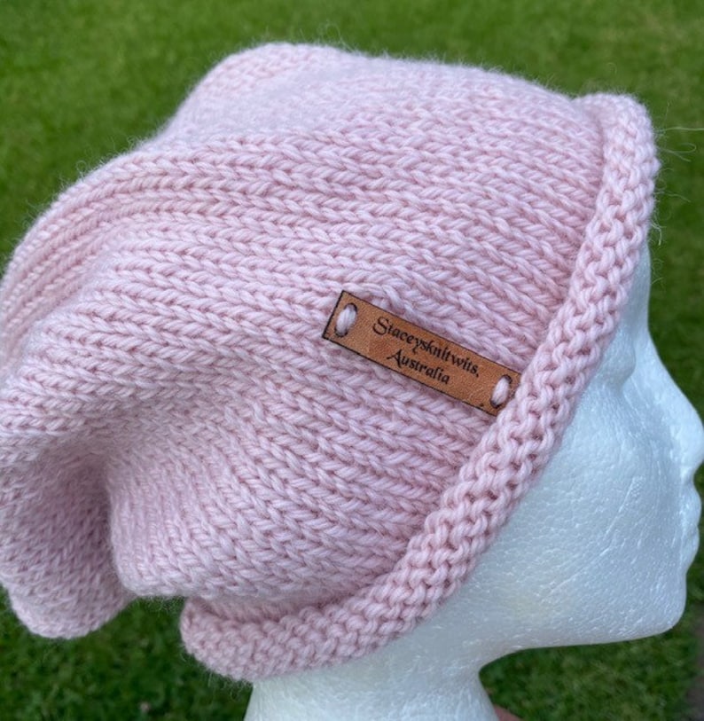 May include: A pink knitted beanie with a brown leather label that reads "Stacey's Knitwits, Australia".