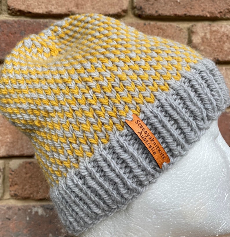 May include: A gray and yellow knitted beanie with a brown leather tag that reads "Stacey's Knits Australia".
