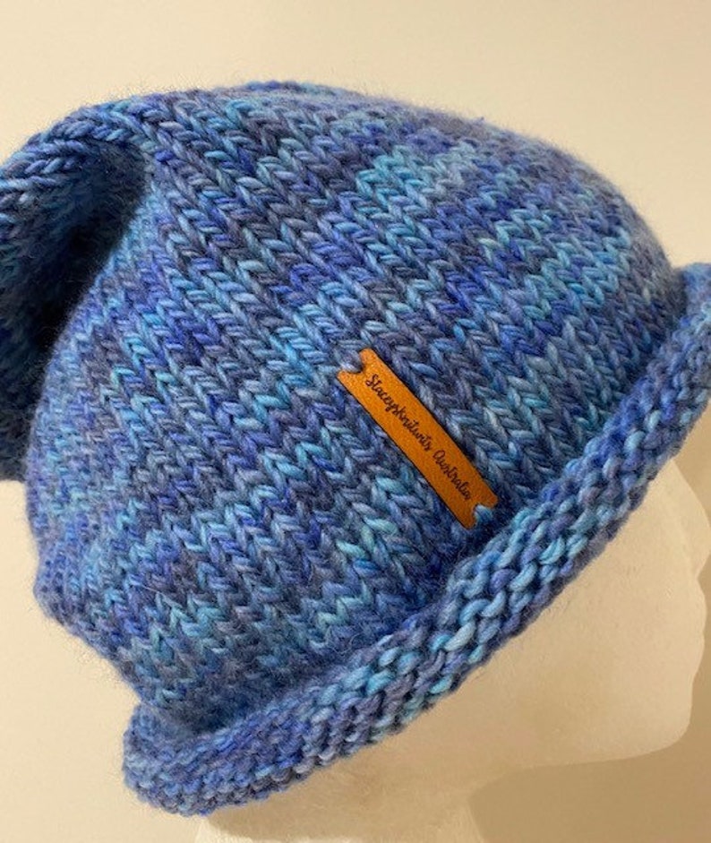 May include: Blue and teal knitted beanie with a brown leather tag that reads "SleepyKnitter's Australia".