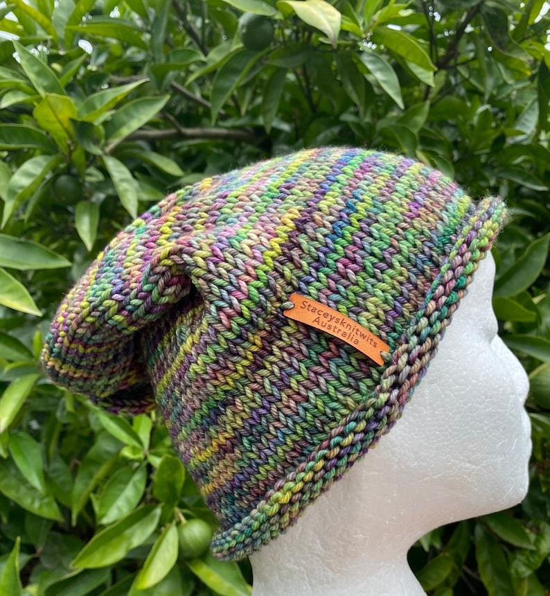 May include: A colorful knitted beanie hat with a brown leather tag that reads "Stacey's Knits Australia".
