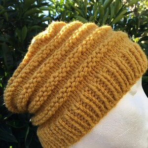 Pode incluir: Um gorro de malha amarelo mostarda com um ajuste folgado. O gorro &eacute; feito com um padr&atilde;o de ponto texturizado.