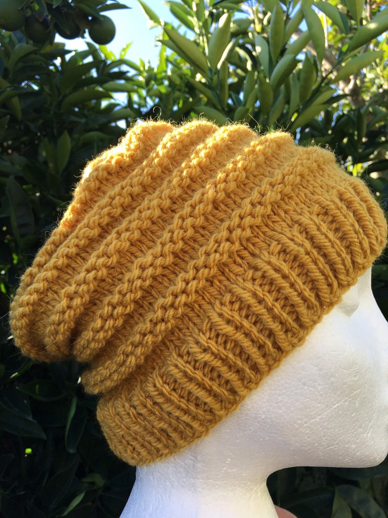 Pode incluir: Um gorro de malha amarelo mostarda com um ajuste folgado. O gorro &eacute; feito com um padr&atilde;o de ponto texturizado.
