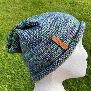 May include: A blue, green, and purple striped knitted hat with a brown leather tag that says "Staceyknits Australia".