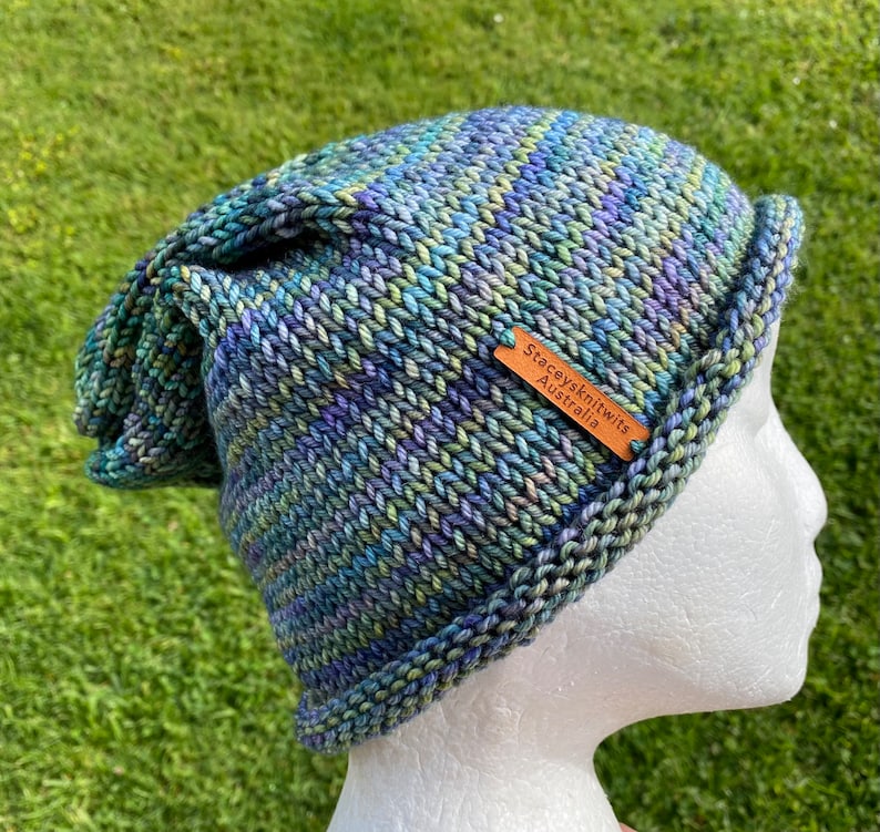 May include: A blue, green, and purple striped knitted hat with a brown leather tag that says "Staceyknits Australia".