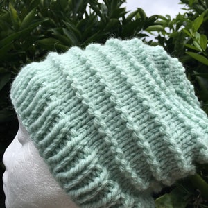 Pode incluir: Um gorro de malha de cor verde claro com textura canelada. O gorro &eacute; feito de fio macio e tem um ajuste folgado.