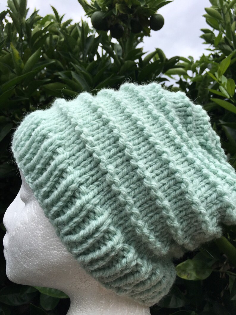 Pode incluir: Um gorro de malha de cor verde claro com textura canelada. O gorro &eacute; feito de fio macio e tem um ajuste folgado.