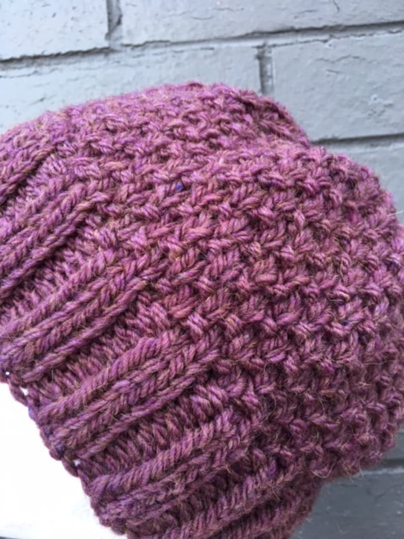 May include: A purple knitted beanie hat with a textured stitch pattern.