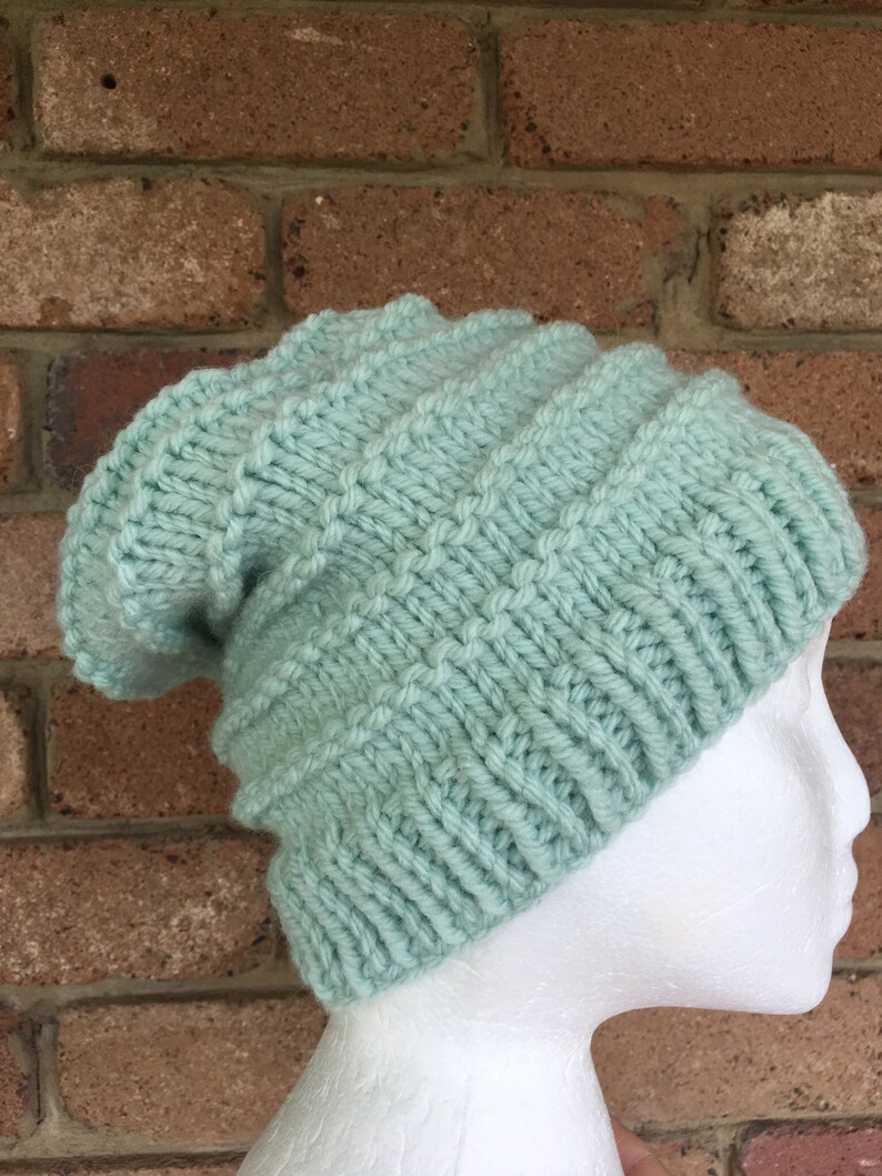 Pode incluir: Um gorro de malha de cor verde claro com um ajuste folgado. O gorro &eacute; feito com um padr&atilde;o de ponto texturizado.