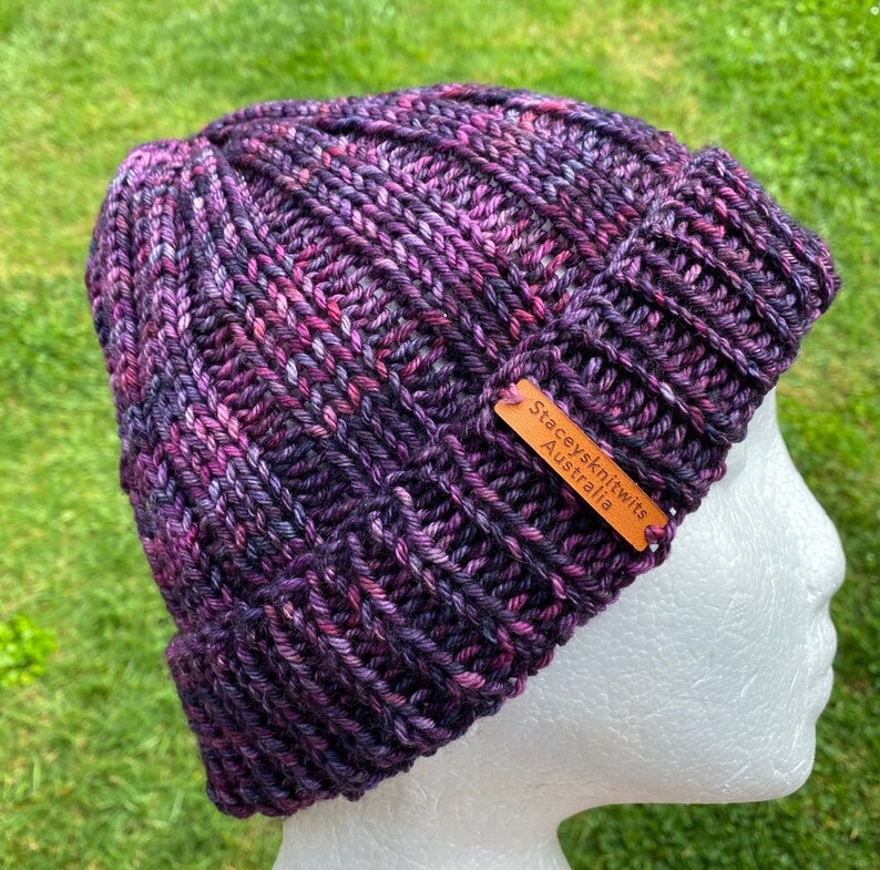 May include: Purple and pink knitted beanie with a brown leather tag that reads "Stacey's Knits Australia".