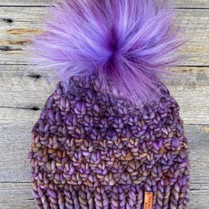 May include: Purple and brown knitted beanie with a large purple and white pom pom. The beanie has a leather tag that says "StaceyKnits Australia".