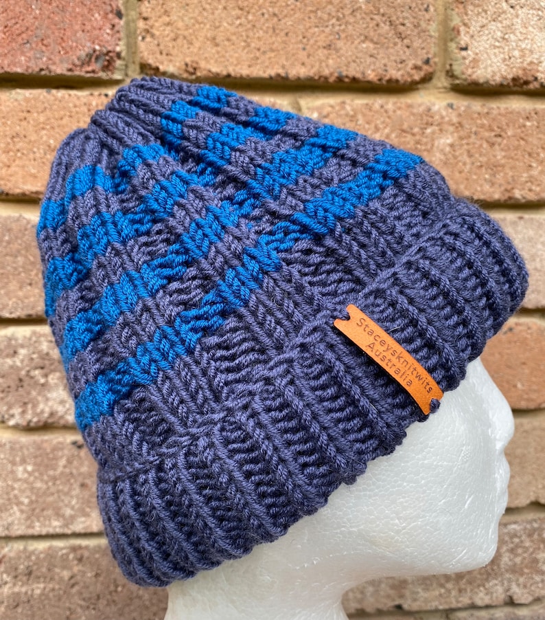 May include: A dark blue knitted beanie with blue stripes and a brown leather tag that reads "Stacey's Knits Australia".