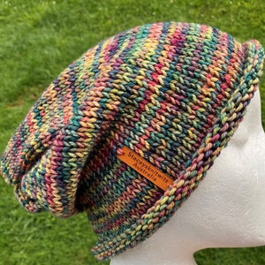 May include: Multicolored knitted beanie hat with a brown leather tag that reads "Stacey's Knitwits Australia".