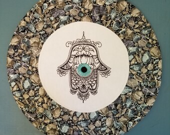 Circular wall or door hanging, or trivet, on "underwater pebbles" design fabric in gray blue and black, Hamsa amulet embroidery, a talisman