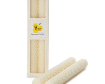 Op de afbeelding: Een pakket handgerolde bijenwaskaarsen met een honingraatpatroon. De verpakking toont de tekst "Little Bee" en "Hand Rolled Beeswax Candles". Twee extra kaarsen worden naast de doos getoond.