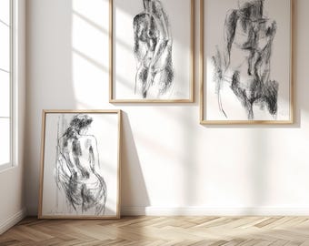 Könnte beinhalten: Drei gerahmte Wandbilder mit schwarzen Kohleskizzen menschlicher Figuren auf weißem Papier. Jeder Druck befindet sich in einem hellen Holzrahmen und zeigt ausdrucksstarke, gestische Linien, die die Form und Haltung der Motive einfangen.