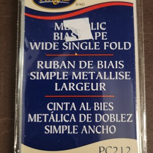 May include: A package of gold metallic wide single fold bias tape. The package is labeled "Wrights Metallic Bias Tape Wide Single Fold" in English, French, and Spanish. The package also includes the product code "PC212" and the measurements "3 yd/2.74 m .875 in wide 22.22 mm de large/ancho".