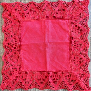 May include: A square, red, handmade doily with a central solid red square and a decorative, openwork crochet border. The crochet border features a scalloped edge and intricate patterns.